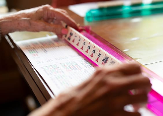 Hands playing Mahjong on a game table