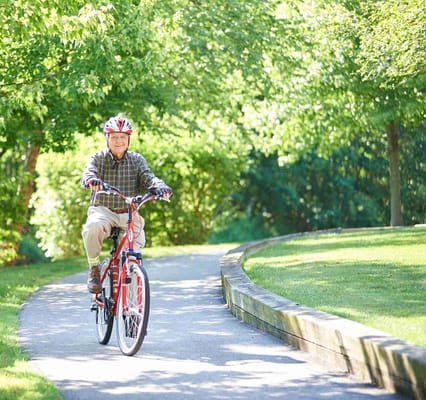 Senior man riding a bike on a sunny path