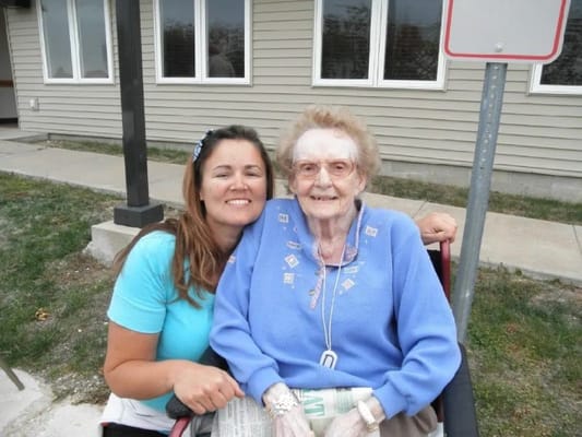 A staff member and resident smiling outdoors