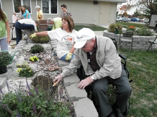 Residents gardening outdoors with staff assistance