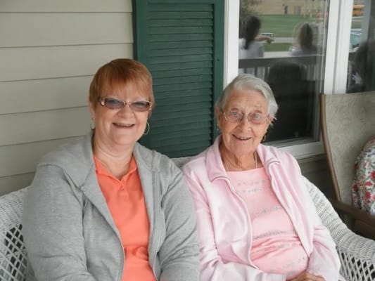 Two smiling women sitting on a porch