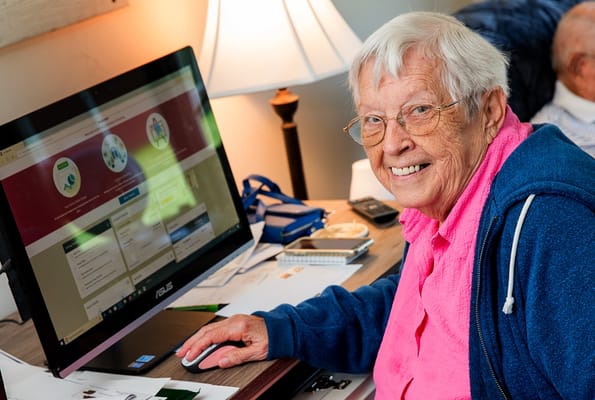 A smiling resident using a computer in a bright room