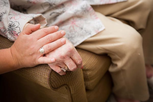 Close-up of hands resting on a chair