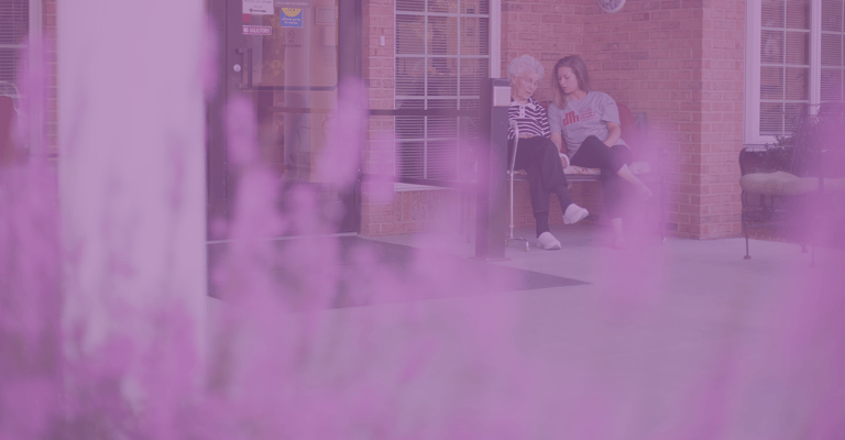 Elderly resident and staff member on a patio