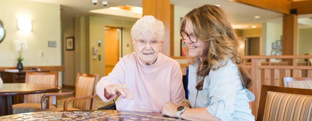 A resident and staff member working on a puzzle together