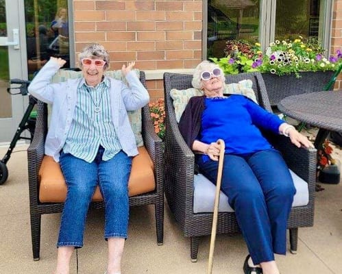 Two seniors enjoying chairs outdoors with smiles