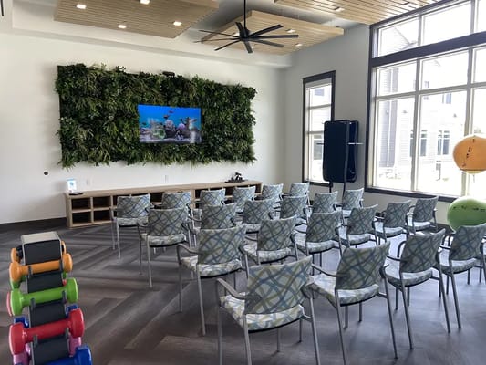 Bright common area with seating and a large screen