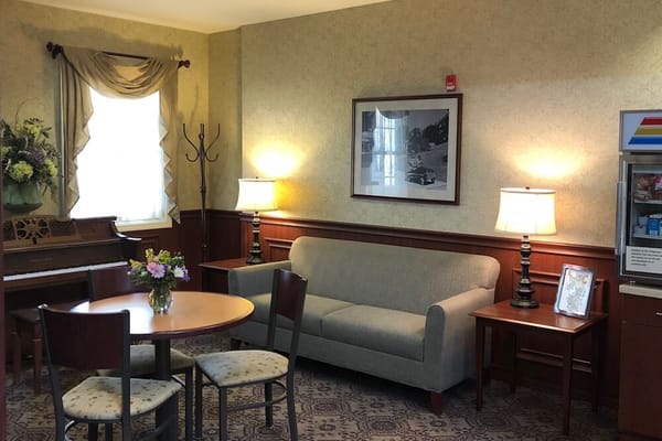 Cozy common area with seating, flowers, and piano