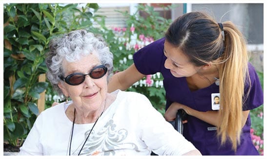 Senior resident with caregiver in an outdoor garden