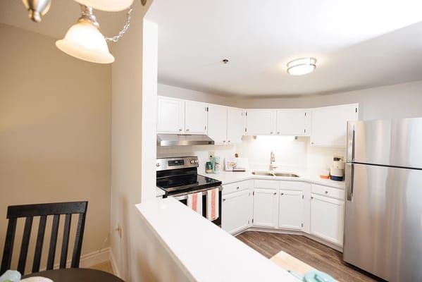 Bright kitchen area with white cabinetry and appliances