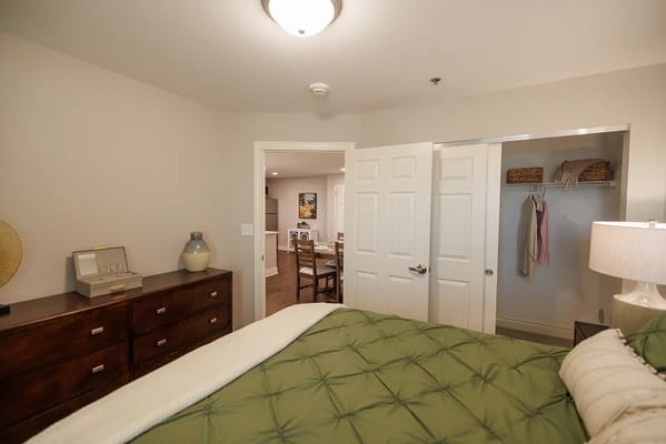 Cozy resident bedroom with green bedding and wooden furniture