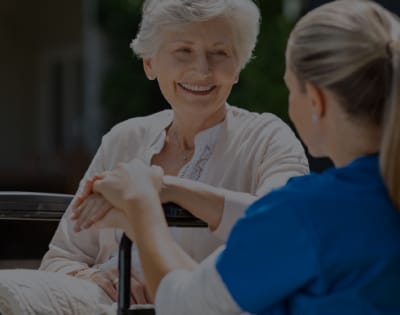 A caregiver smiling with a resident outdoors