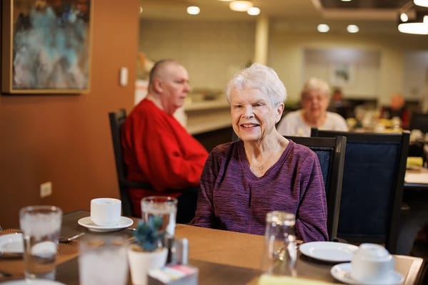 A smiling resident enjoying a meal in the dining room