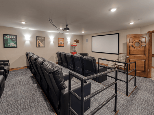 Cozy private theater room with black recliners and a projector