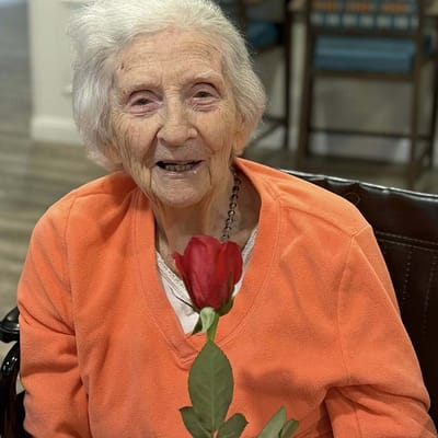 An elderly resident smiling while holding a rose