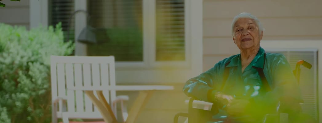 An elderly woman smiling on a patio