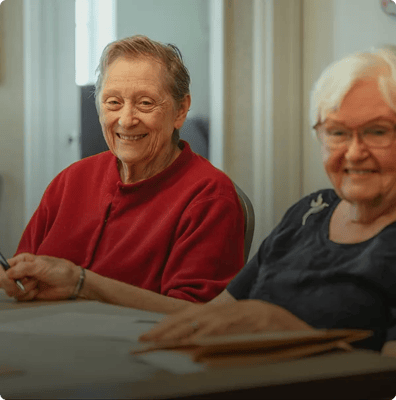 Two smiling senior residents in a cozy activity room