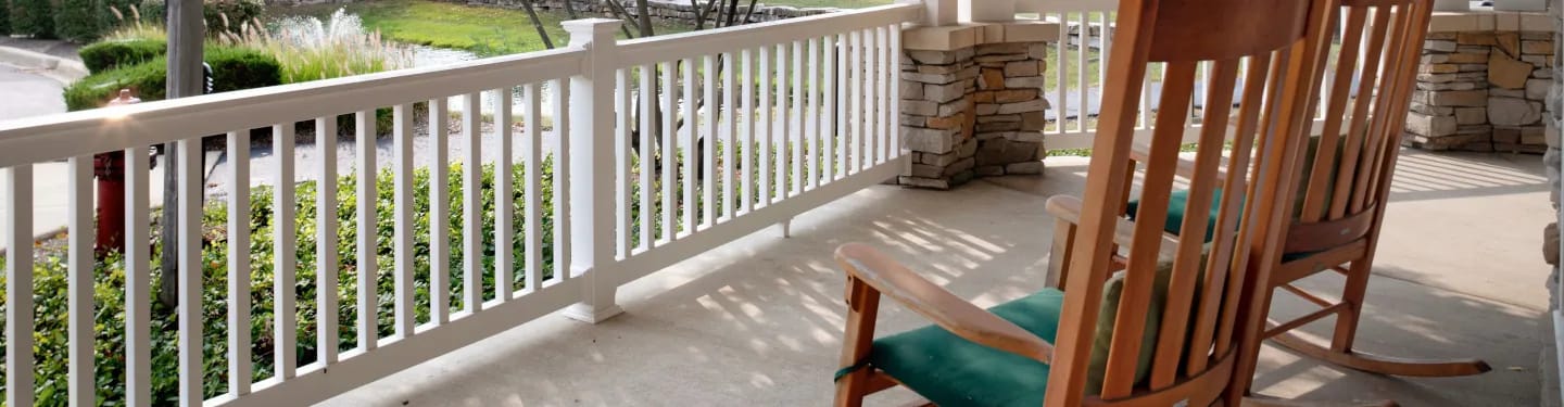 Empty rocking chairs on a porch overlooking green space