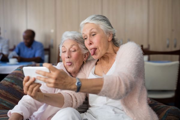 Two elderly women taking a selfie in a common area