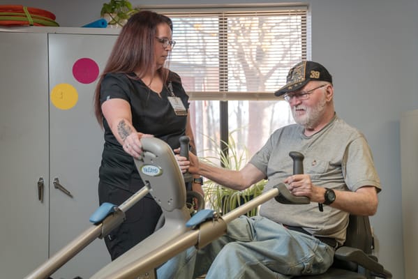 Staff assisting a resident with exercise equipment