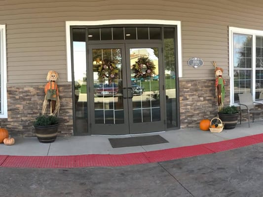 Front entrance decorated for fall with pumpkins and scarecrows