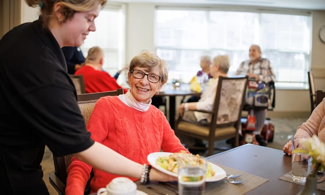 Resident enjoying a meal with staff in the dining room