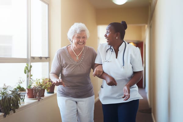 Nurse assisting a senior resident in a hallway