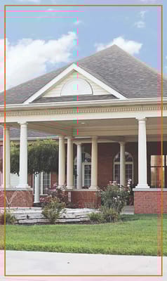 Exterior view of assisted living facility with porch and landscaping