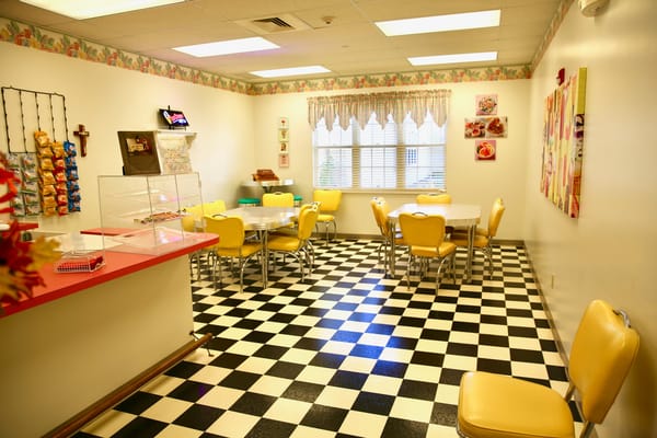 Bright dining room with checkered flooring and yellow chairs