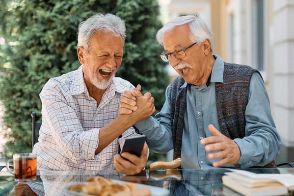 Two elderly men enjoying a laugh together outdoors
