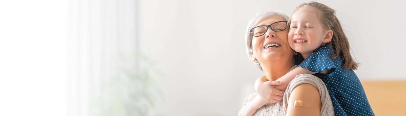 A smiling woman with glasses and a girl embracing