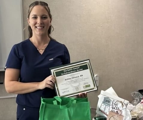 Nurse holding DAISY Award in an interior setting