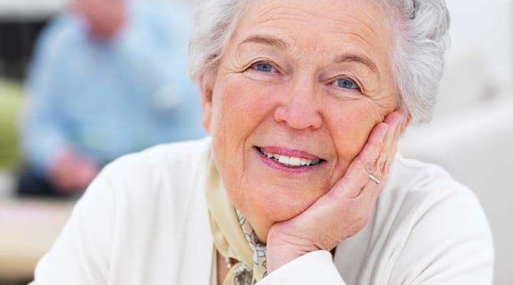 Smiling elderly woman with gray hair resting her head on her hand