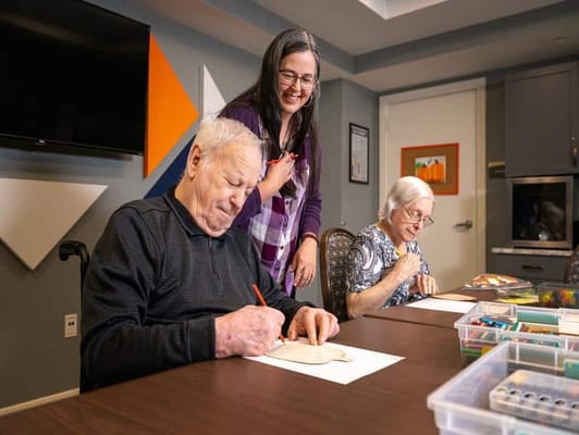 Residents engaging in an art activity with staff assistance
