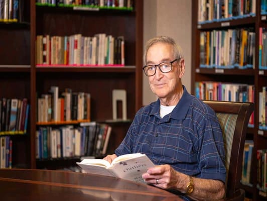 An older man reading a book in a library setting