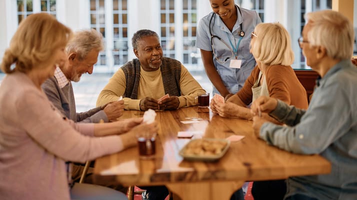 Residents enjoying a card game with staff assistance