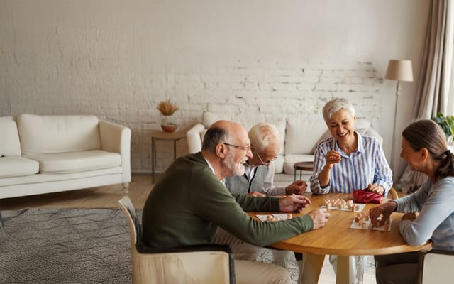 Seniors playing a game together in a cozy common area