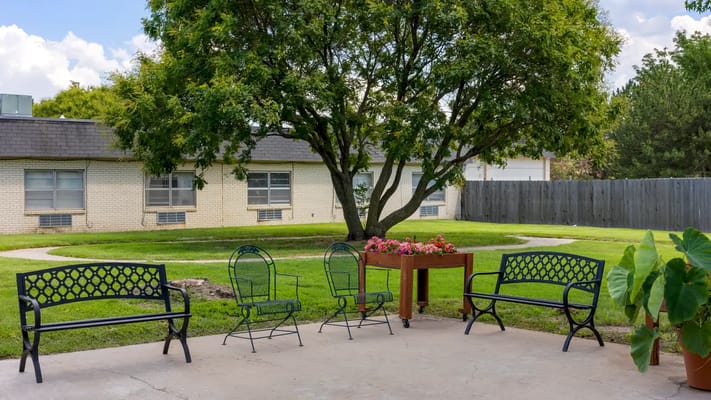 Outdoor seating area with green grass and trees