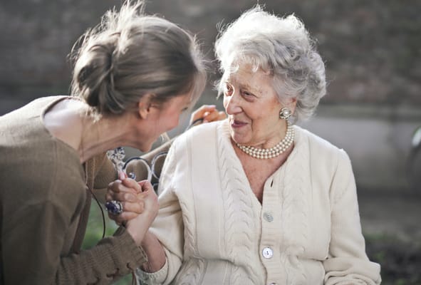 Resident interacting with staff outside in a garden
