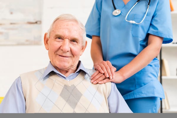 A smiling elderly man with a caregiver