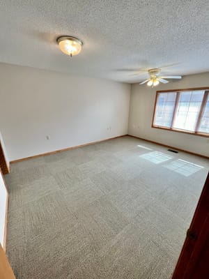 Empty resident room with a ceiling fan and windows