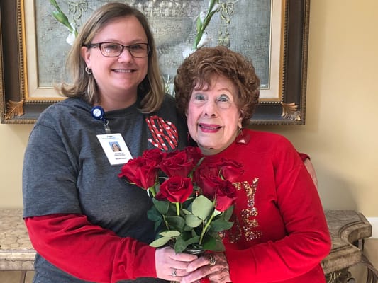 Staff member holding roses with a resident in a common area