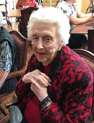 A smiling elderly resident in a red jacket