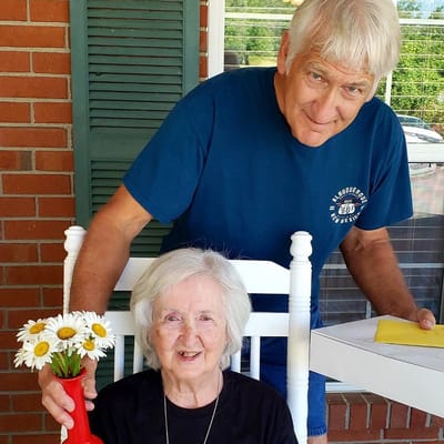 A man presenting flowers to a smiling woman on a porch