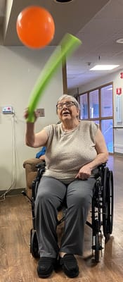 An elderly resident enjoying a balloon activity in a common area