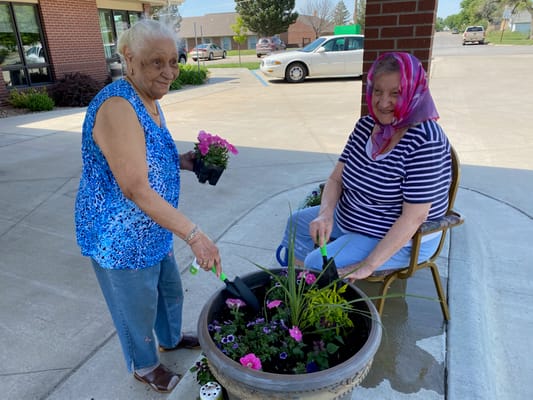 Two residents planting flowers in a garden area