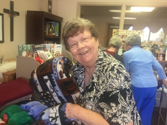 A resident smiling while holding a blanket in a common area.