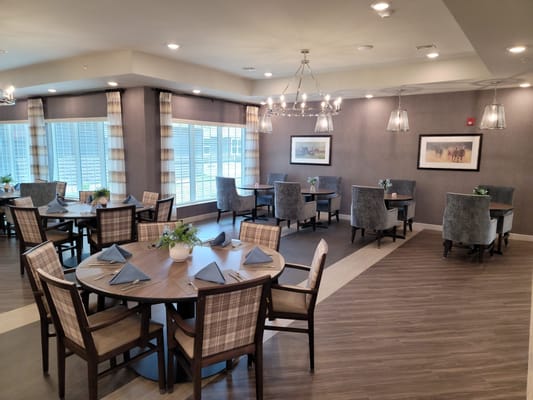 Brightly lit dining room with tables and chairs arranged