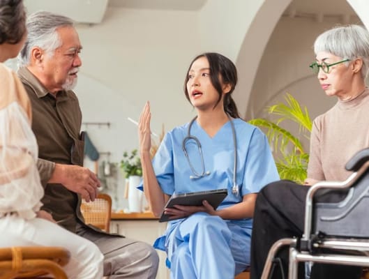 A healthcare professional speaking with residents in a bright common area