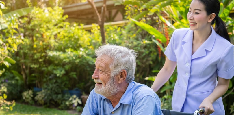 Caregiver pushing a resident in a garden